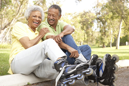 elderly couple laughing and sitting wearing roller blades