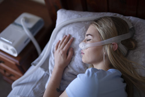 young blonde asleep wearing sleep apnea device