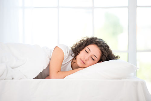 peaceful young woman asleep on bed