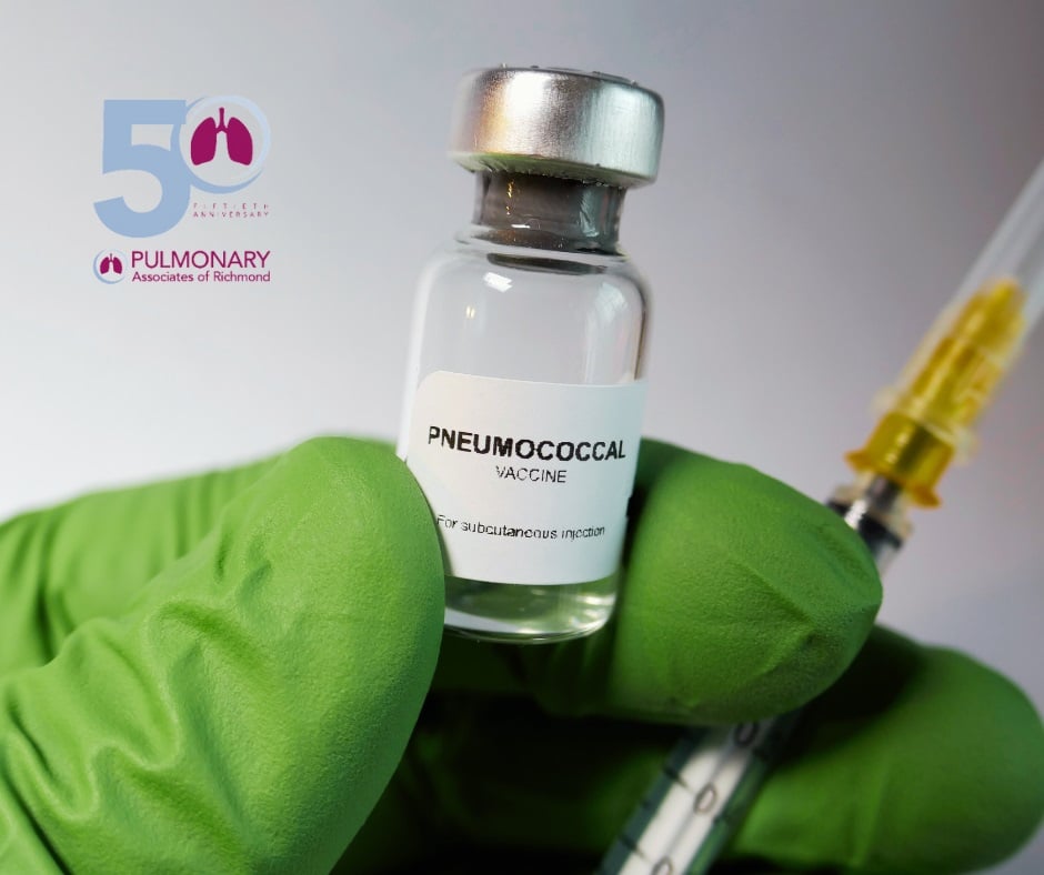 Close up of fingers wearing green latex gloves holding a vial of pneumococcal vaccine