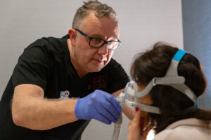 Sleep technician adjusts a mask on a patient's face in preparation for a sleep study.